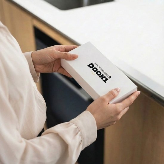 Een persoon houdt een witte doos vast met de tekst 'DOOK1 MAGNETIC TOWEL HOLDER'.
