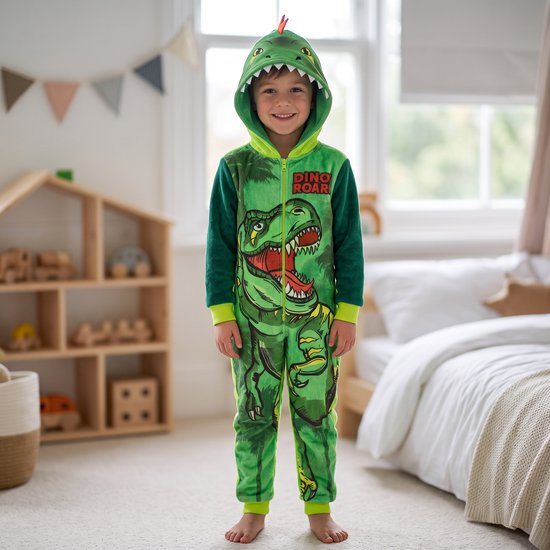 Kind draagt een groene Disney onesie met dinosaurusprint en capuchon met tanden, tekst 'DINO ROAR!'