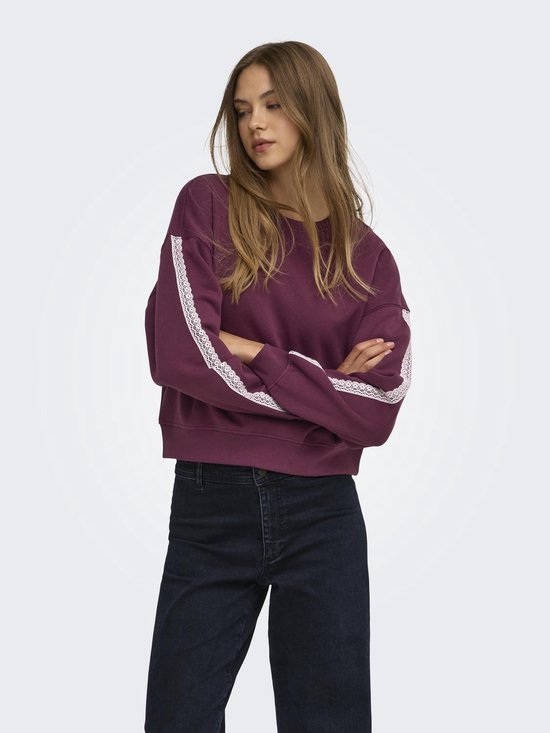 Model draagt een donkerrode sweater met witte kanten details langs de mouwen en een ronde hals.