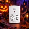 Witte bewegingssensor voor Halloween, met lens bovenaan, indicatorlampje en luidspreker in een sfeervol decor.
