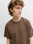 Close-up van model in bruin t-shirt met borstzakje en Jack & Jones label.
