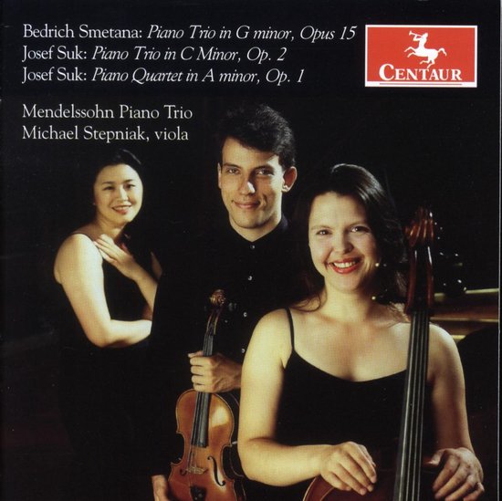 Drie musici staan glimlachend tegen een donkere achtergrond. Een vrouw links met viool, een man in het midden met viool, en een vrouw rechts met cello.