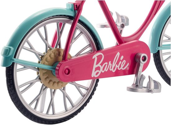 Detail van de roze Barbie fiets, met 'Barbie' logo op de trapas en zilveren spaakwielen.