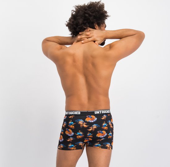 Man van achteren gezien die zijn nek strekt, draagt een zwarte boxershort met exotische visprint.