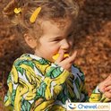 Kindje met krullend haar in een kleding met bananenprint bijt op een gele ster.