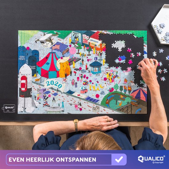 Vrouw legt puzzel op zwarte mat, puzzel toont satirische kijk op 2020 met raket, circus en protesten.