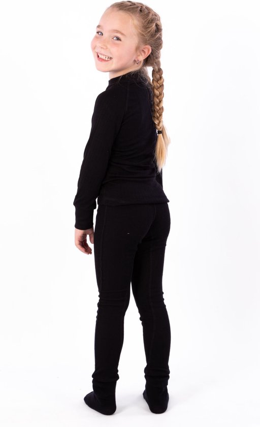 Lachend meisje met blonde vlechten, draagt een zwarte thermobroek en thermoshirt.