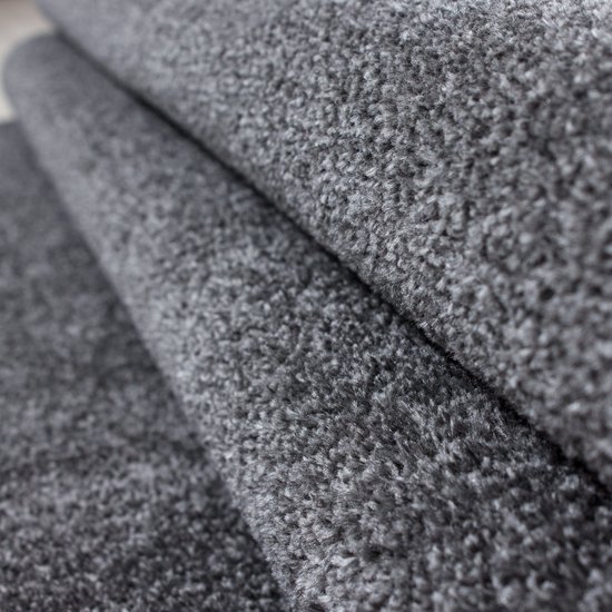 Tapis gris foncé à poils courts plié, partiellement visible avec un bord retourné.