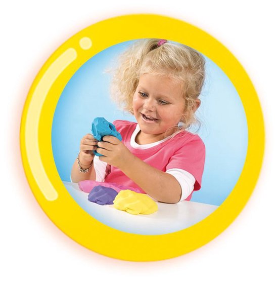 Een jong meisje met blond krullend haar in een roze shirt, die blauwe klei in haar handen heeft. Rondom haar liggen roze, paarse en gele kleibolletjes.