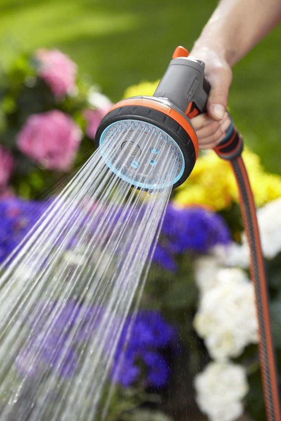 Grijze GARDENA spuit met oranje en blauwe accenten sproeit fijne waterstralen.