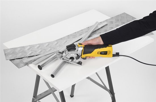 Gele met zwarte mini invalzaag, in gebruik bij het zagen van metalen buizen en diamantplaten op een werktafel.