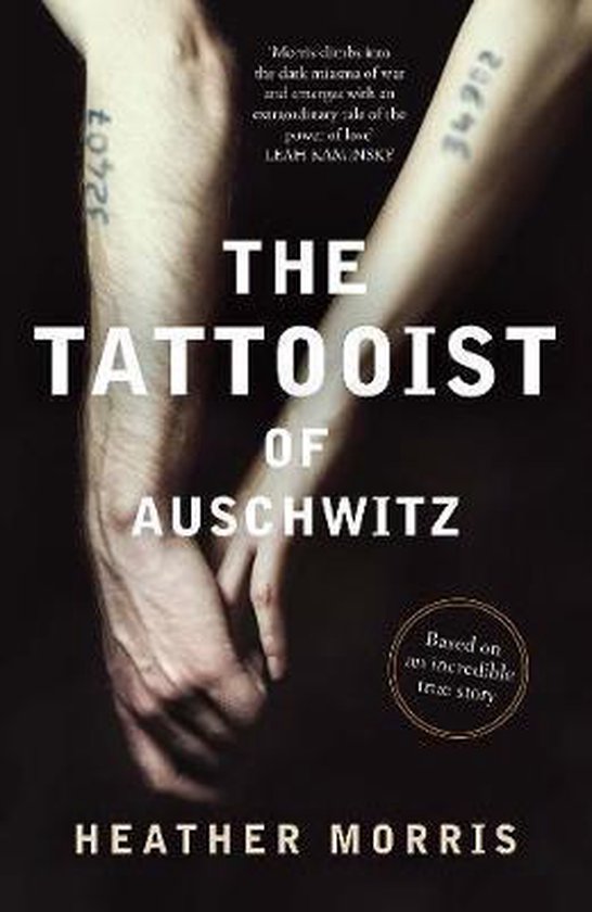 De kaft van het boek 'The Tattooist of Auschwitz' toont twee armen met tatoeage nummers op. De titel en auteursnaam zijn duidelijk zichtbaar.