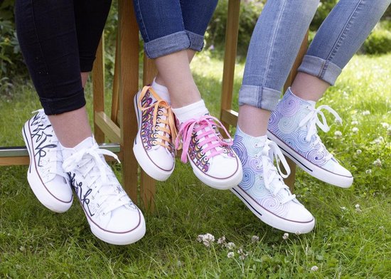 Drie paar witte sneakers met kleurrijke patronen: zwart kalligrafisch, oranje en roze, en blauw en paars spiraal.
