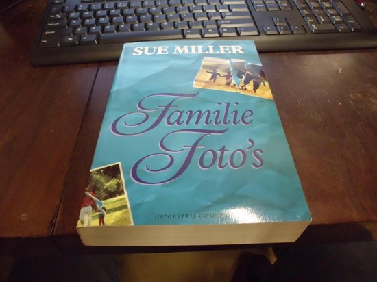 Boek 'Familie Foto's' van Sue Miller met een blauwe omslag met foto's van kinderen die spelen en een golfspeler.