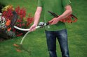 Man houdt oranje Black+Decker grastrimmer vast, met een extra kop.