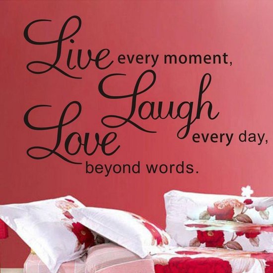 Sticker mural noir avec texte 'Live every moment, Laugh every day, Love beyond words.' sur mur rouge au-dessus d'un lit.
