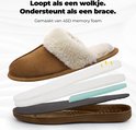 Exploded view van een bruine pantoffel met witte teddy voering, die de lagen van memory foam en de zool toont.