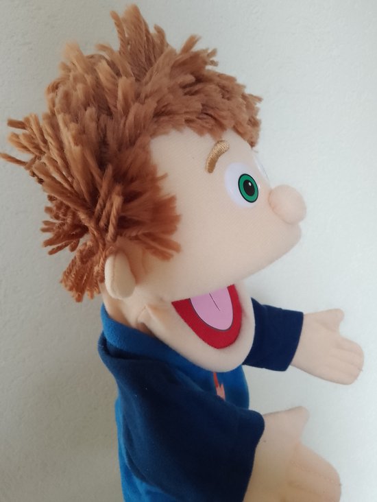 Zij aanzicht van een handpop met bruin warrig haar, groene ogen, open mond met rode binnenkant en roze tong. Draagt een blauw shirt.
