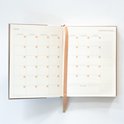Opengeklapte planner met maandoverzicht en notitieruimte.