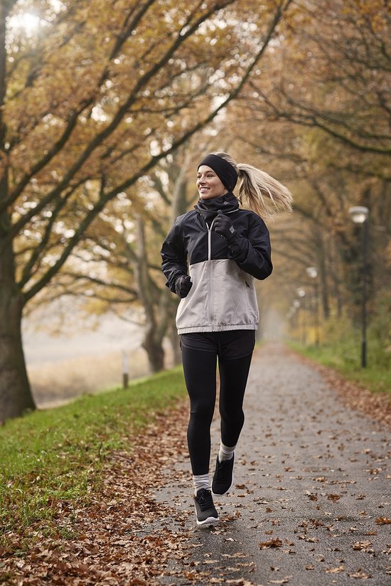 Vrouw met paardenstaart die jogt op een herfstachtig pad in een zwarte legging.