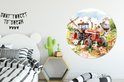 Een ronde muurcirkel met een rode tractor en boerderijdieren, in een kinderslaapkamer met een zwart-wit bed en een cactuslampje.