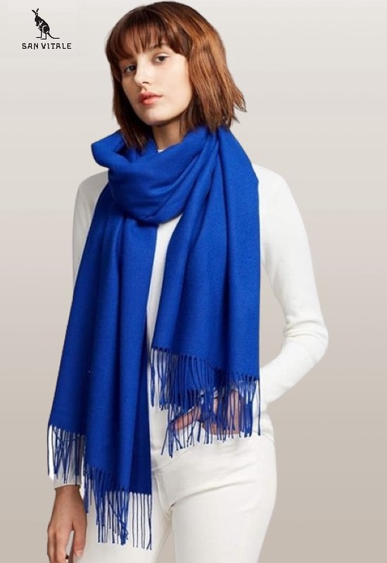 Model met koningsblauwe pashminasjaal met franjes, gedragen met een witte coltrui en witte broek.