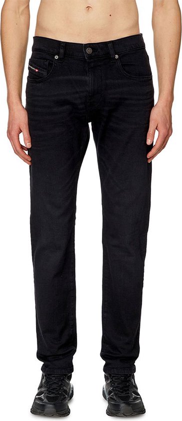 Man in zwarte jeans, van voren gezien. De broek heeft zakken aan de voorkant.