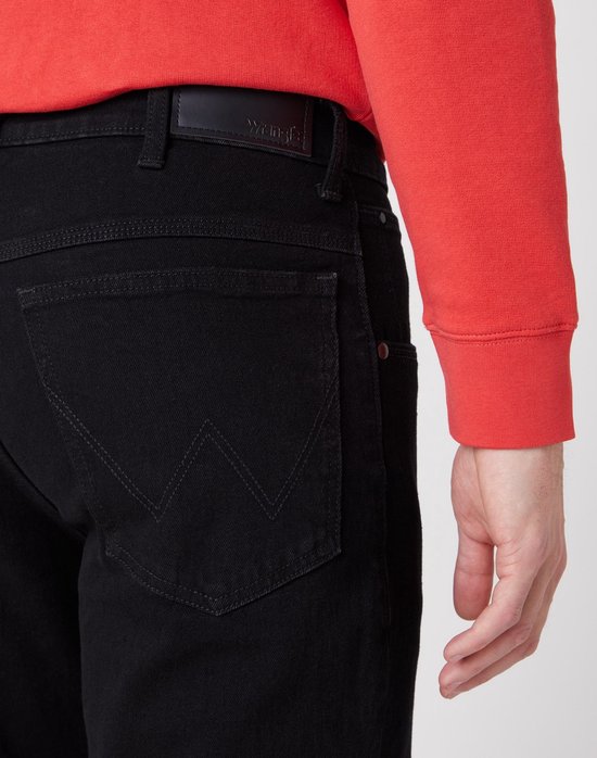 Detail van de achterzakken van een zwarte jeans met Wrangler logo.