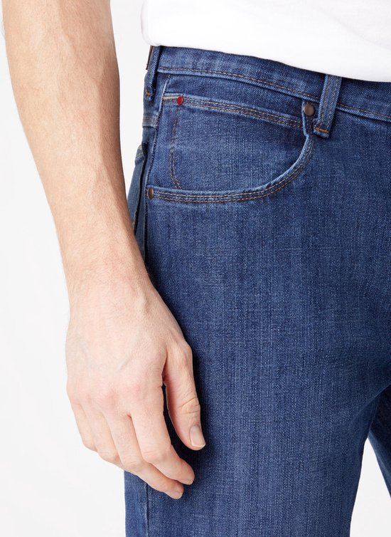 Detail van de voorkant van een donkerblauwe jeans met zakken.