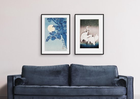 Deux gravures japonaises sur un mur au-dessus d'un canapé bleu foncé.