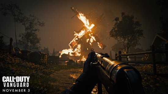 Perspectief van de speler met een geweer, kijkend naar een brandend vliegtuig op een donker, herfstachtig pad. Call of Duty: Vanguard.
