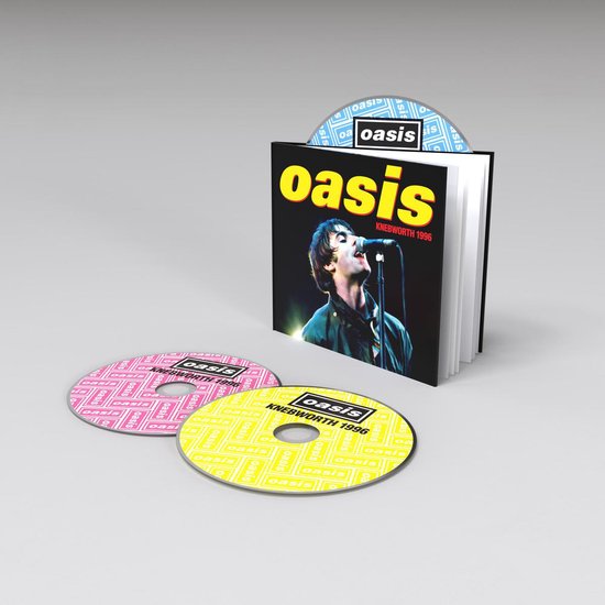 Oasis Knebworth 1996 CD set met boek. Twee cd's, één roze en één geel, met een patroon van het Oasis-logo. Een ingevoegde cd is zichtbaar met een blauw patroon.