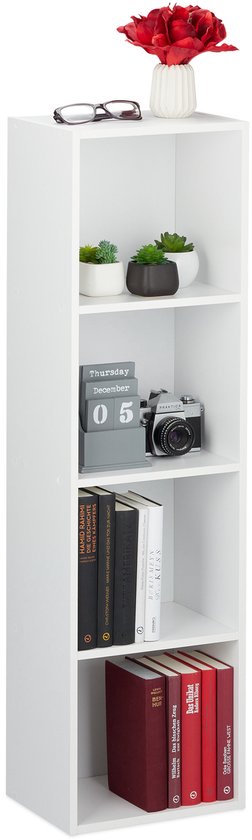 Hoge smalle witte boekenkast met vier vakken, gevuld met boeken, plantjes, een camera en een vaas met bloemen.