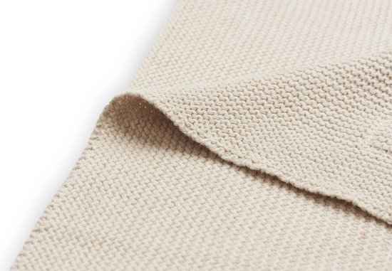 De naden en textuur van een beige gebreide babydeken.