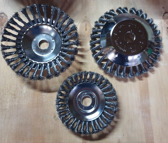 Drie stalen onkruidborstels van verschillende groottes, gelegen op een houten ondergrond.