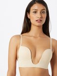 Vrouw met nude MAGIC Bodyfashion V-Bra met diepe V-hals en afneembare bandjes.