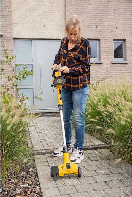 Vrouw met gele onkruidverwijderaar met wielen en steel, in een tuin.