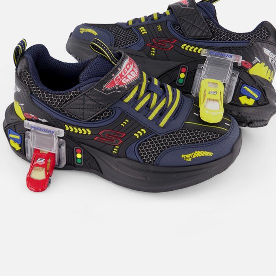 Paar blauwe sneakers met raceauto-details, gele veters en lichtjes inclusief kleine speelgoedauto's.