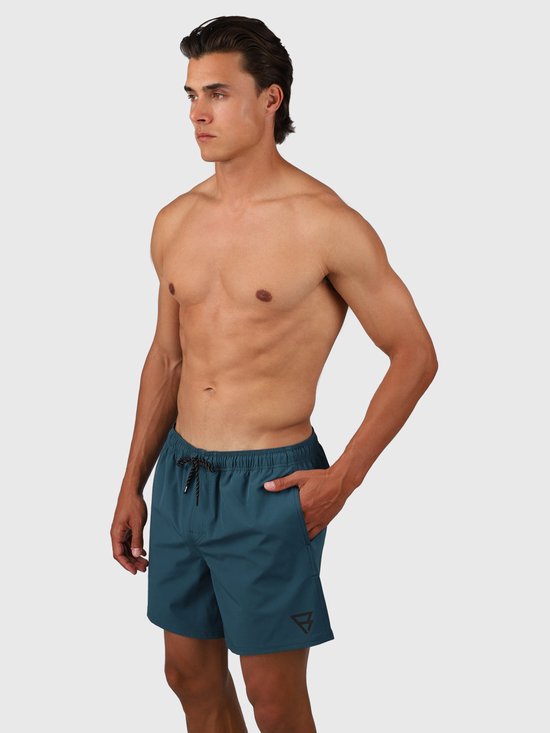 Homme portant un maillot de bain vert Fuel. Le maillot de bain a un cordon de serrage et un logo sur la jambe gauche.