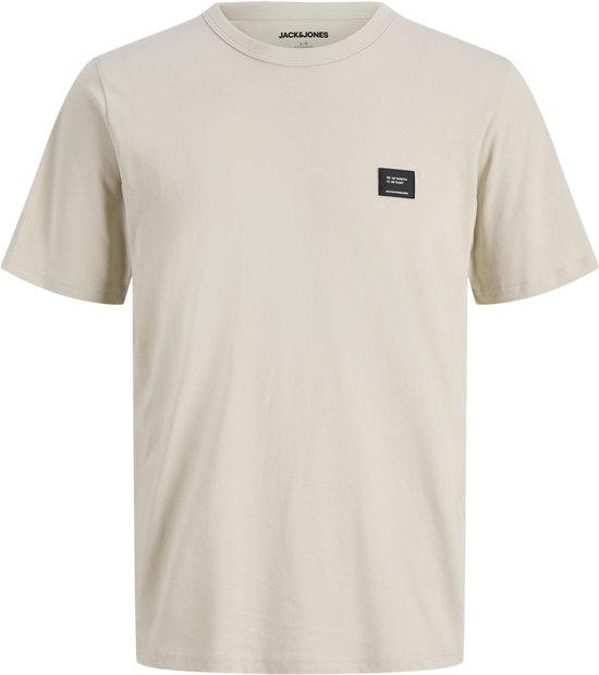 Un t-shirt beige à manches courtes avec un petit patch noir marqué sur le côté gauche de la poitrine.