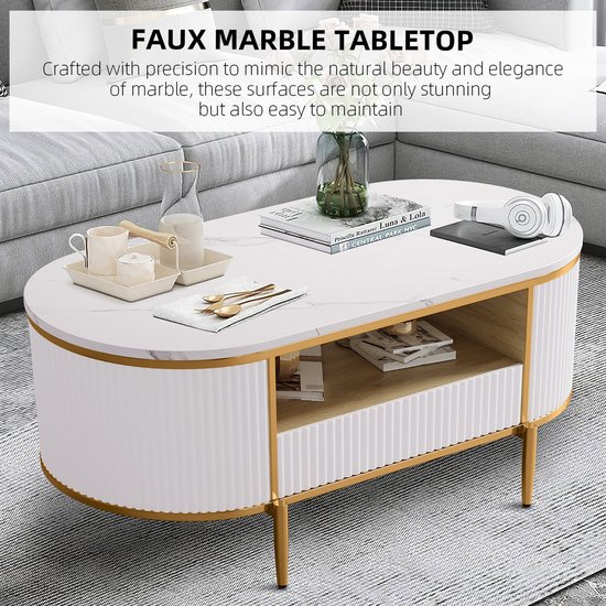 Ovale salontafel met marmerlook blad, wit geribbeld design en gouden poten. Met open vakken en een lade.