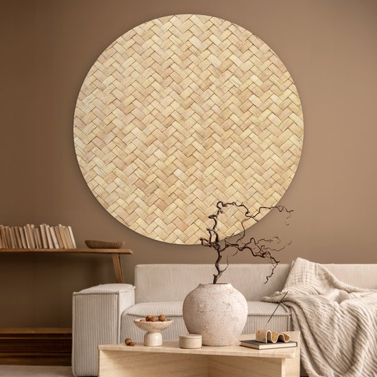 Décoration murale ronde en rotin avec motif tressé, au-dessus d'un canapé crème.