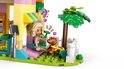 Gros plan d'une mini-poupée LEGO Friends tenant un chiot marron en laisse devant une animalerie rose et jaune.
