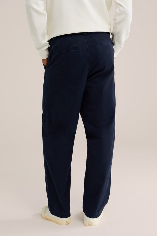 Donkerblauwe chino, gedragen door een model. De achterkant van de broek is zichtbaar.