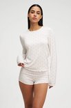Model met witte pyjamaset met rode hartjes, lange mouwen en korte broek.