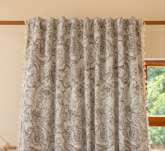 Crèmekleurige gordijnen met een bruine barokprint en zijkanten versierd met crèmekleurige franjes.