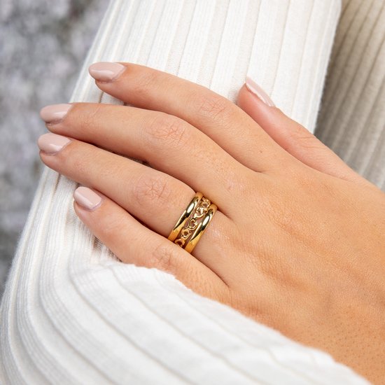 Gouden stapelringen met schakelpatroon gedragen op een hand met lichte nagellak.