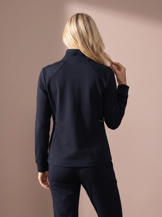 Vrouw in donkerblauw sportvest met witte bies, van achteren gezien.