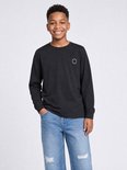 Jongen met een zwarte longsleeve en distressed jeans.