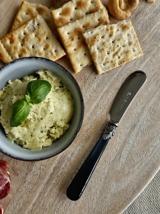 Boterhammes met zwarte handgreep en decoratieve zilverkleurige versiering, met boter en crackers.
